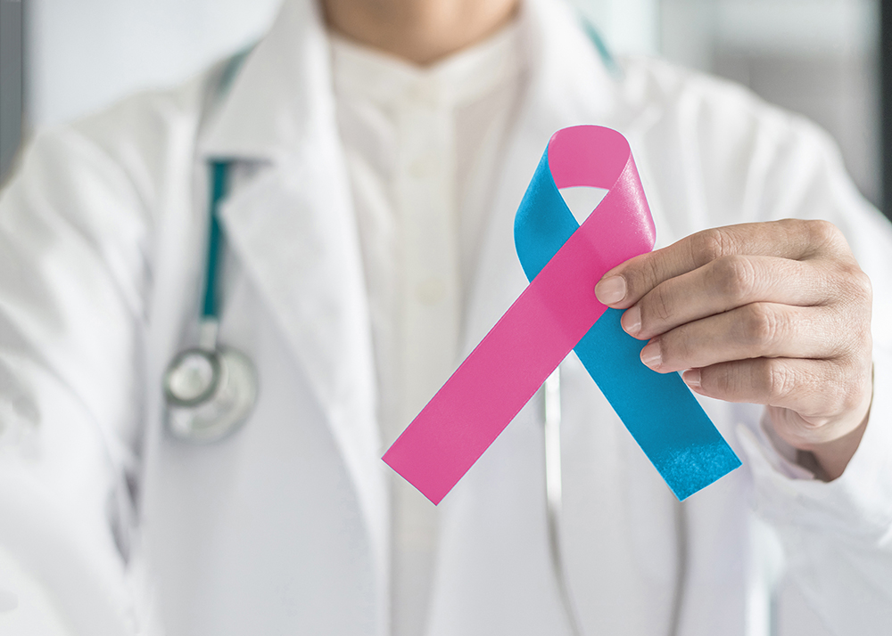 Médico com um laço azul e rosa nas mãos, simbolizando a importância da conscientização da infertilidade.